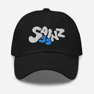 Pode incluir: Boné de beisebol preto com texto bordado em branco e azul que diz "Sainz 55".