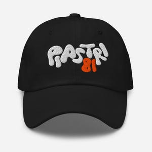 Pode incluir: Boné de beisebol preto com o texto "PASTRI 81" bordado em branco em uma fonte de bolhas. O número 81 está em laranja.
