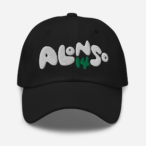 Pode incluir: Boné de beisebol preto com o texto bordado "ALONSO 14" em branco e verde. O boné tem uma aba curva e uma alça ajustável. Um acessório elegante para os fãs.
