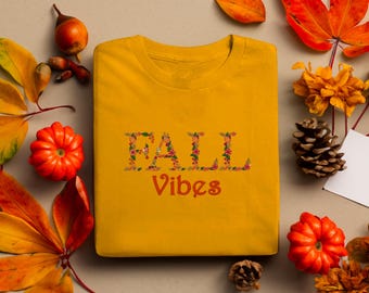 May include: A yellow t-shirt with the text "FALL Vibes" in orange letters surrounded by fall-themed floral designs.