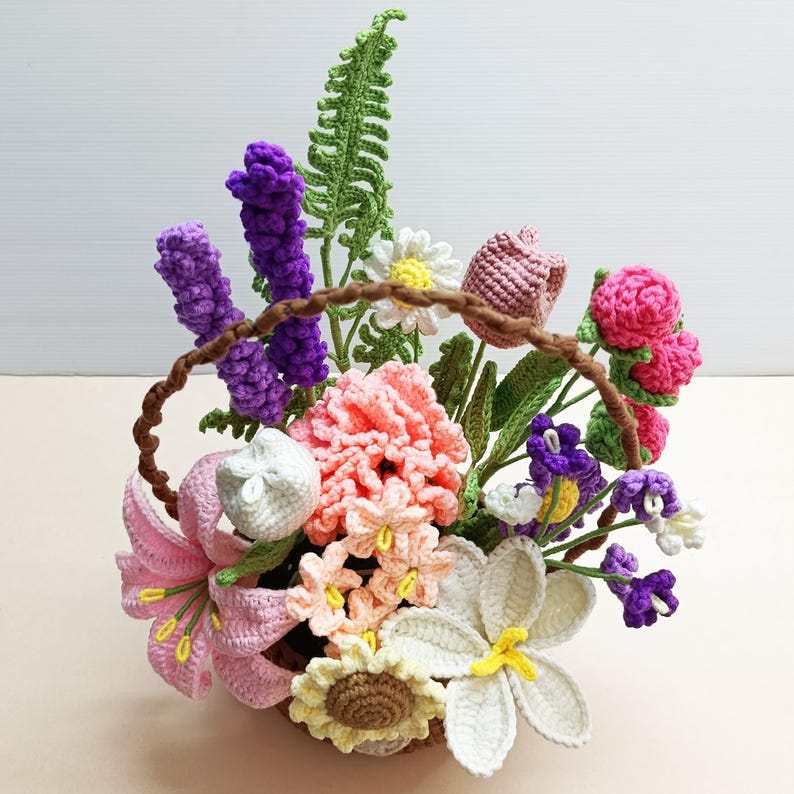 May include: A crocheted flower arrangement in a brown basket. The arrangement includes pink, white, purple, and yellow flowers, as well as green leaves.