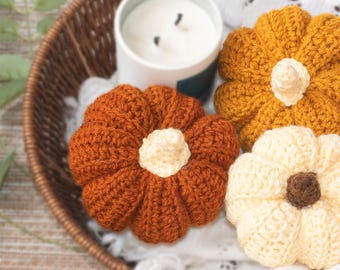 May include: Three crocheted pumpkins in a wicker basket. The pumpkins are orange, yellow, and cream colored.