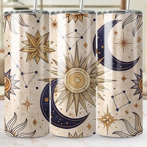Puede incluir: Tres vasos de acero inoxidable con un diseño celestial. Los vasos presentan un fondo crema con cuerpos celestes dorados y azules, incluyendo lunas, estrellas y soles.
