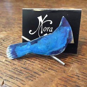 Può includere: Uno spillo per cravatta in metallo blu a forma di uccello con un gambo argentato. L'uccello è appollaiato su un gambo argentato. L'uccello è un ghiandaia azzurra.