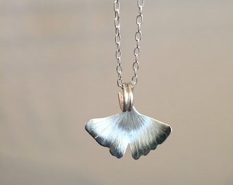 May include: A silver chain necklace with a ginkgo leaf pendant.