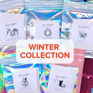 May include: Five holographic pouches containing scented putty, each with a white label featuring the text THE'S STUDIOS and specific illustrations for Sugarplum Fairy, Christmas Wreath, Cranberry, Hot Cocoa, and Snow Fairy.