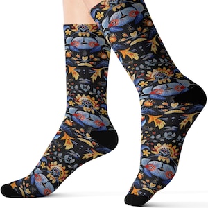 May include: A pair of crew socks with a black background and a colorful floral pattern. The design features blue, yellow, and orange flowers and leaves. The socks have black heels and toes.