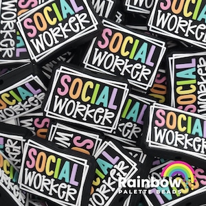 May include: A close-up of a pile of colorful silicone charms with the text "SOCIAL WORKER" in a rainbow font. The charms are black with white outlines and are perfect for adding a personal touch to bags, keychains, or jewelry.
