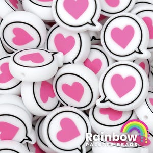 May include: White and pink heart-shaped beads. Each bead features a pink heart inside a white speech bubble with a black outline. The beads are round and have a hole for stringing. The text "Rainbow Palette Beads" is visible.