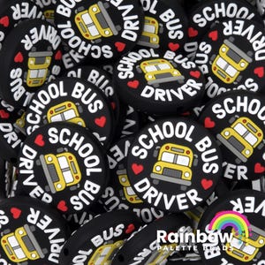 May include: A collection of round black silicone beads featuring a yellow school bus graphic, the text SCHOOL BUS DRIVER in white, and small red hearts. The beads are designed for crafting and jewelry making with a hole for stringing.