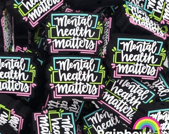 May include: A close-up of a pile of black and white charm beads with the text "Mental health matters" in colorful lettering. The beads are arranged in a random pattern and are all the same size.