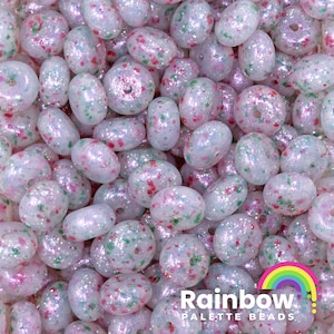 May include: A close-up of a pile of iridescent oval beads. The beads are white with pink, red, and green speckles. The text "Rainbow PALETTE BEADS" is in the bottom right corner.