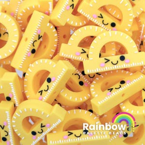 May include: A pile of yellow plastic protractors with white markings and cute cartoon faces. The protractors are about 1 inch in diameter.