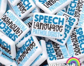 May include: A close-up of a pile of white and blue square-shaped beads with the text "Speech Language Pathologist" printed on them. The beads are perfect for making jewelry or other crafts.