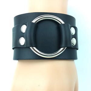 以下が含まれることがあります： 大きな銀色のリングと銀色のスタッズが付いた黒い革のブレスレット