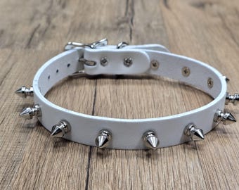 May include: White leather choker with silver metal spikes.