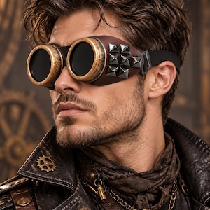 May include: Brown goggles featuring round, distressed gold-tone rims with dark lenses. The side panels are made of brown material adorned with a cluster of silver-tone pyramid studs, secured by a black elastic strap for a snug fit.