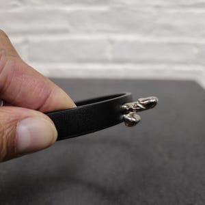 May include: Black leather embroidery hoop with silver metal tightening mechanism.