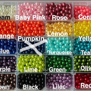 May include: A clear plastic storage container with thirty compartments filled with round, glossy beads in various colors. The colors are labeled as white, cream, baby pink, rose, coral, pink, peach, orange, pumpkin, lemon, yellow, blue, turquoise, teal, purple, lime, green, olive, grey, taupe, brown, black, lilac, red, and silver.