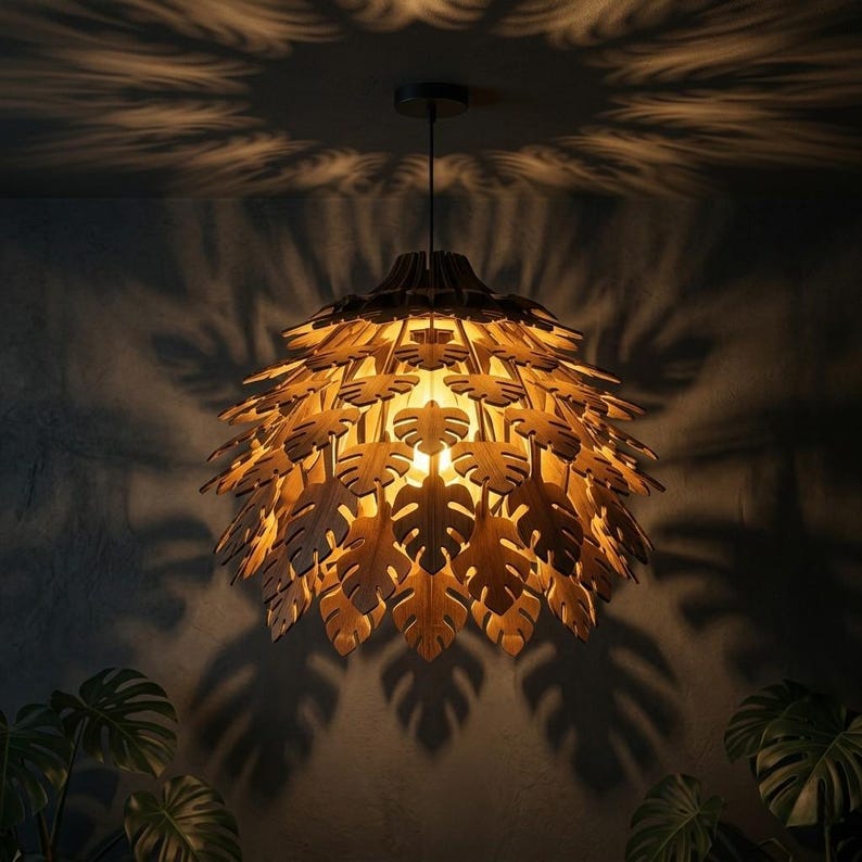 May include: A wooden pendant light fixture with a leaf design. The light is suspended from the ceiling and casts leaf-shaped shadows on the wall. The fixture has a warm, inviting glow, and the leaves are intricately cut.