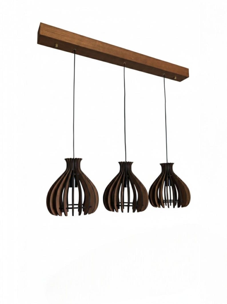 May include: Three pendant lights with a dark brown wooden shade in a teardrop shape, suspended from a rectangular wooden beam. The shades have a slatted design, and the cords are black. The background is white.