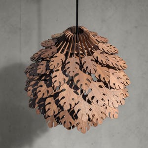 May include: A wooden pendant light fixture with a layered design. The light features a series of leaf-shaped cutouts, creating a natural, organic aesthetic. The fixture is suspended from a black cord, offering a warm, inviting glow.