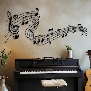 Può includere: Arte da parete in metallo nero che raffigura un design di note musicali. L'opera è esposta sopra un pianoforte nero con uno sgabello bianco. Una chitarra acustica marrone è appoggiata a una sedia sullo sfondo.