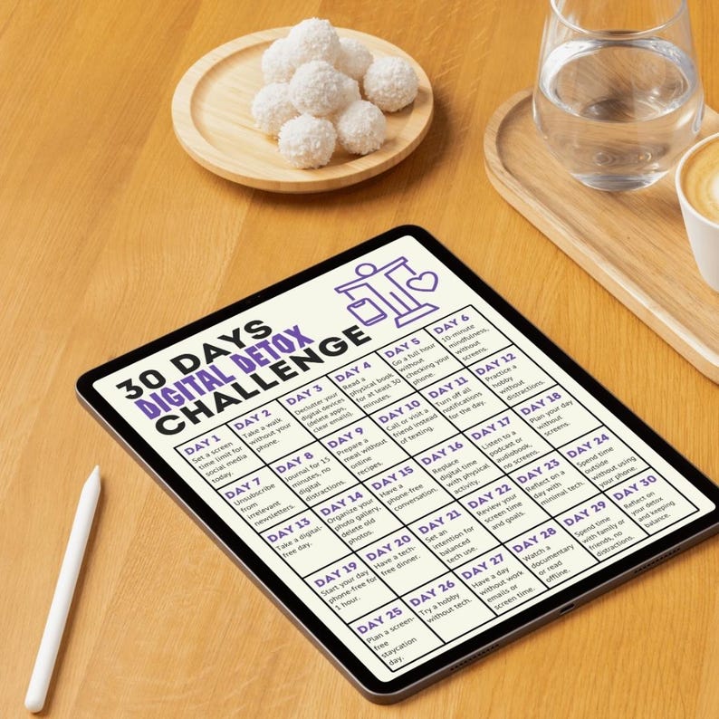 Peut inclure: Un d&eacute;fi de d&eacute;sintoxication num&eacute;rique sur un &eacute;cran de tablette avec un calendrier de 30 jours. Chaque jour propose une activit&eacute; diff&eacute;rente pour vous aider &agrave; r&eacute;duire le temps pass&eacute; devant les &eacute;crans. La tablette est pos&eacute;e sur une table en bois avec un verre d'eau et une tasse de caf&eacute;.