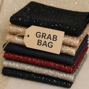 May include: A stack of fabric squares in various colors, including black, gold, navy, and red, covered in sequins. A brown tag with the words "GRAB BAG" hangs from the stack.