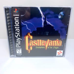 May include: A PlayStation game case for Castlevania: Symphony of the Night. The case is black with a red and yellow title card. The game is rated T for Teen by the ESRB.