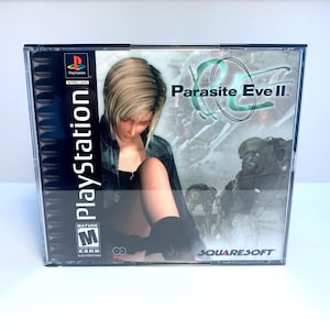 Peut inclure: Une boîte de jeu PlayStation pour Parasite Eve II, avec une femme en tenue noire sur la couverture. Le jeu est classé M pour Mature par l'ESRB et est publié par SquareSoft.