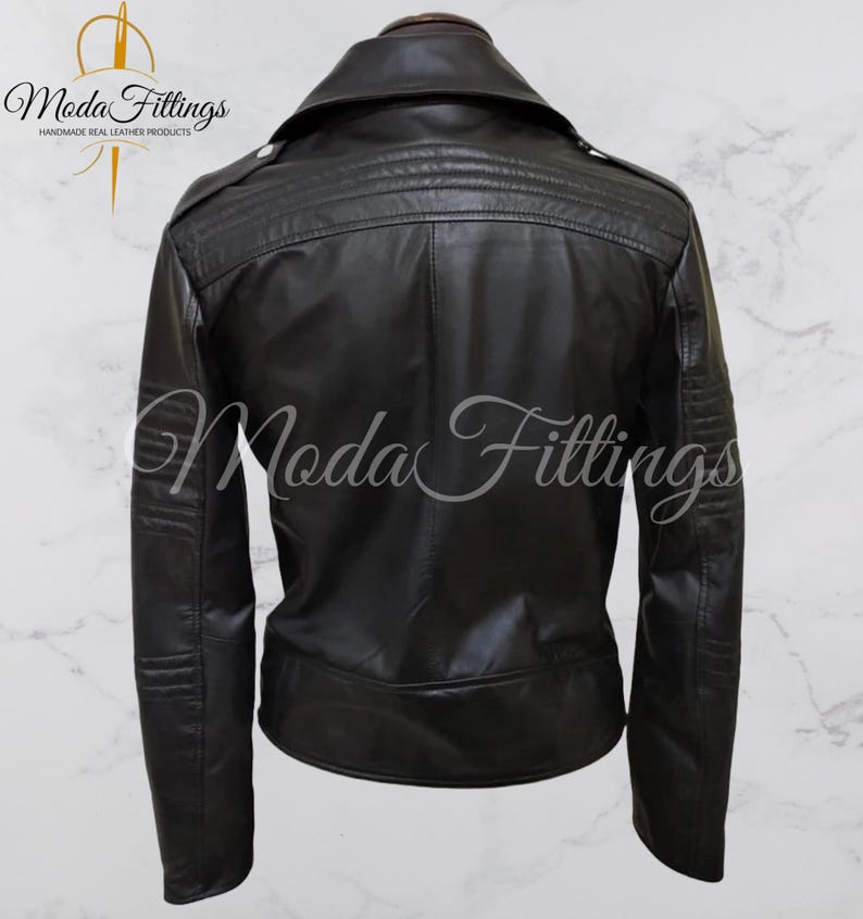 May include: Black leather jacket with a zipper closure and a collar. The jacket has a quilted design on the back and a logo that says "Moda Fittings Handmade Real Leather Products".