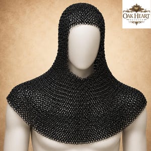 May include: Black chainmail coif and gorget displayed on a mannequin. The coif covers the head and neck, while the gorget protects the shoulders. The metal armor is made of small, interlocking rings. The Oak Heart Outfits logo is in the upper right corner.