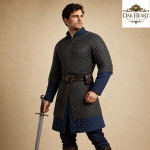 May include: A medieval chainmail shirt with blue quilted sleeves and a matching blue tunic. The shirt is worn with a brown leather belt and a small pouch. A silver sword is held in the hand. The logo for Oak Heart Outfits is in the upper right corner.