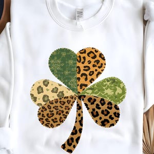 Op de afbeelding: Witte crewneck sweatshirt met een groot klaverbladontwerp. Het klaverblad bestaat uit verschillende patronen, waaronder luipaardprint en groene bloemenmotieven. Deze casual sweatshirt is geschikt voor St. Patrick's Day of dagelijks gebruik.