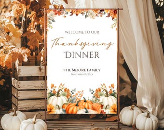 May include: Thanksgiving dinner sign with a copper frame. The sign reads "Welcome to our Thanksgiving Dinner" with the family name and date. The sign is decorated with pumpkins and fall foliage. White pumpkins are in the foreground.