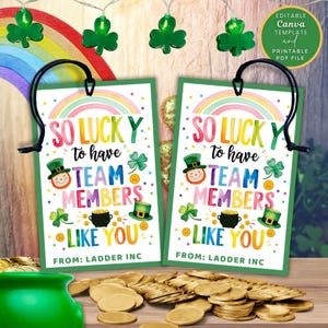 May include: Two St. Patrick's Day gift tags with the text "So Lucky to have Team Members Like You" and a rainbow design. The tags feature a leprechaun, pot of gold, and shamrocks. The tags are hanging with black string.