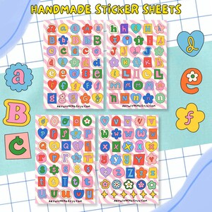 May include: Four sheets of handmade alphabet stickers with a retro aesthetic. Each sticker sheet features colourful letters in various shapes, including hearts and flowers, against a pink and white striped background. The text "ARTWITHCHO.ETSY.COM" is at the bottom of each sheet.