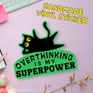 May include: Green vinyl sticker featuring a black cat lying on its back with the text "Overthinking is my superpower" in white lettering. The sticker is handmade and has the text "Handmade Vinyl Sticker" in yellow lettering at the top.