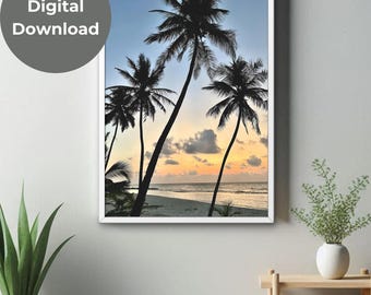 May include: Silhouette of palm trees on a beach at sunset. The sky is a gradient of blue, pink, and orange. The water is calm and the sand is white.