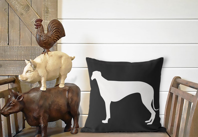 May include: Black and white throw pillow with a white silhouette of a greyhound dog on a black background.