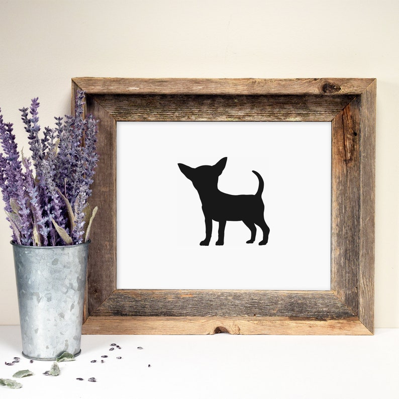 May include: A black silhouette of a chihuahua dog in a white frame with a rustic wood finish. The frame is sitting on a white surface with lavender flowers in a metal vase.