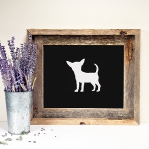 May include: A white silhouette of a chihuahua dog on a black background in a rustic wooden frame.