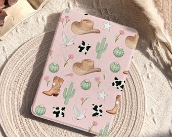 May include: A pink tablet case featuring a repeating pattern of cowboy hats, boots, cacti, stars, and cowhide patches. The case also includes images of doves and flowers. The words "Glow Dwell Designs" are printed on the case.