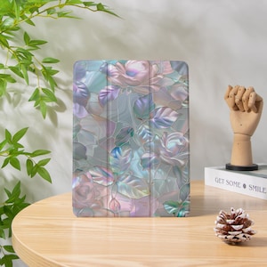 Könnte beinhalten: Tablethülle mit einem Buntglas-Design, das Rosen in Rosa, Blau und Lila zeigt. Das Design hat eine glänzende Oberfläche. Das florale Muster ist vor einem hellgrauen Hintergrund platziert. Die Hülle schützt das Tablet.