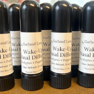 May include: A collection of black and white nasal diffusers. Each diffuser has a black cap and base with a white label that reads "Wake-Upsal Nasal Diffuser" and "Eucalyptus + Peppermint".