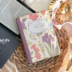 May include: A composition book with a floral design featuring pink, purple, and yellow flowers. The book has a purple spine and the text "Composition Book" and "Justlife's Kindle" is printed on the front cover.