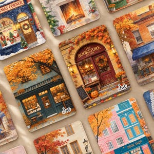May include: A collection of rectangular coasters featuring detailed watercolour-style illustrations of storefronts and seasonal scenes, including a bookstore with autumn leaves, a Christmas shop, and a cosy fireplace, each with a glossy finish.
