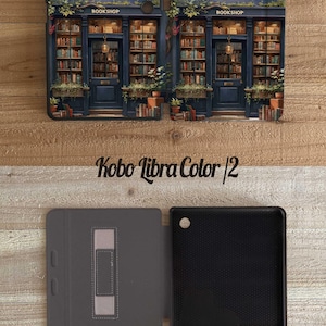 May include: A Kobo Libra Color 2 tablet case with a detailed illustration of a bookstore facade. The case is dark blue with a bookstore design, featuring shelves of books, a door, and the word "BOOKSHOP". The inside of the case is gray and black.