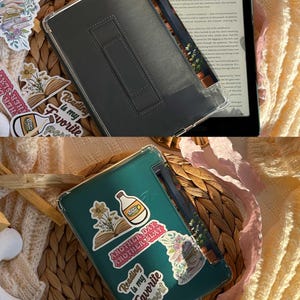 May include: Two e-reader cases, one gray and one teal, with stickers that say "Reading is my Favorite Sport" and "Another Day, Another Slay." The e-readers are open, displaying text. The cases are on a woven basket.